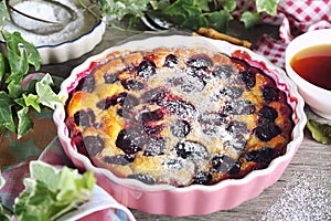 Blue plum clafoutis flan, icing sugar dressing and cup of tea