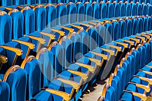 Blue plush chairs with wooden armrests in the auditorium. Empty auditorium in the theater