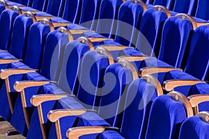 Blue plush chairs with wooden armrests in the auditorium. Empty auditorium in the theater