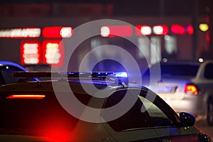 blue police car light at night in city with selective focus and bokeh on black background