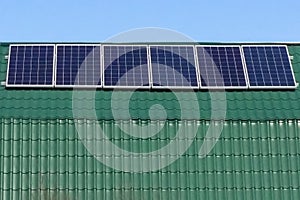 Blue polycrystal solar panels on green roof of house