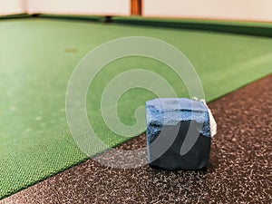 Blue pool chalk leaning on the edge of the pool table