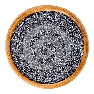 Blue poppy seeds in wooden bowl over white