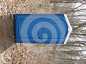 Blue Porta Potty in a woods photo