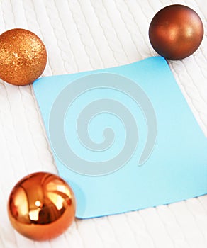 Blue postcard on the background of white texture of woolen fabric with pigtail pattern and orange Christmas toys balls