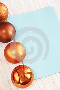 Blue postcard on the background of white texture of woolen fabric with pigtail pattern and orange Christmas toys balls