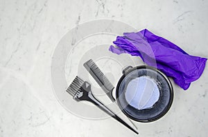 Blue powder hair dye bleaching tools with comb, purple latex gloves and comb on light background photo