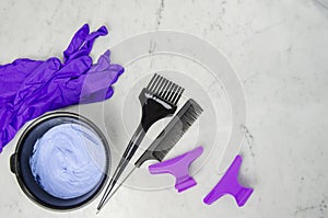 Blue powder hair dye whitening utensils with comb, hair pins and purple latex gloves and comb on light background. photo