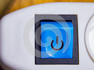 A blue power button with a power icon, set on a white device, suggesting functionality photo