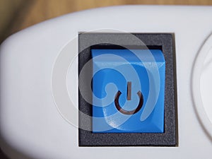 Blue power button on white extension cable. Power button, close-up shot