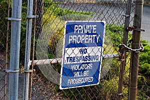 Blue private property no trespassing sign on a chain link fence