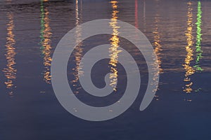 Blue or purple background with bridge lights reflection in river water at night. Soft focus