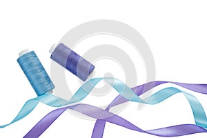 Blue and purple curly satin ribbons, spools of blue and purple thread on a white. Horizontal banner with two satin ribbons and