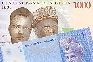 A blue, purple and green one thousand  naira note from Nigeria paired with a blue, plastic one ringgit bank note from Malaysia.