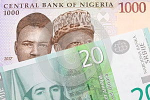 A blue, purple and green one thousand  naira note from Nigeria paired with a green and white twenty dinar banknote from Serbia.