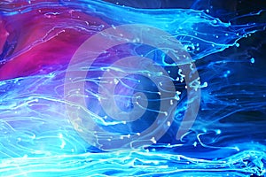 Blue and purple paints and inks swirling together in water background