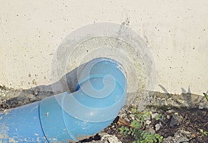 Blue pvc drainage pipe outside the concrete wall.Blue PVC drainage pipe drains into the ground photo
