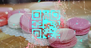 Blue QR code with a red floating web of connections over pink macaronies lying on a table