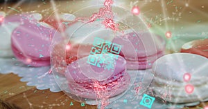 Blue QR code with a red floating web of connections over pink macaronies lying on a table