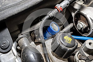 A blue quick-release coupler is installed on the valve from the air conditioning system in the car to fill the R134a refrigerant.