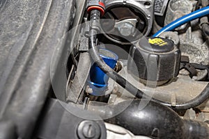 A blue quick-release coupler is installed on the valve from the air conditioning system in the car to fill the R134a refrigerant.
