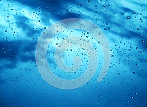 Blue rain drops on window glass background