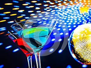 Blue and red cocktail with golden sparkling disco ball background with space for text