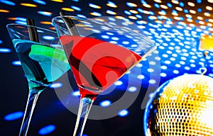 Blue and red cocktail with golden sparkling disco ball background with space for text