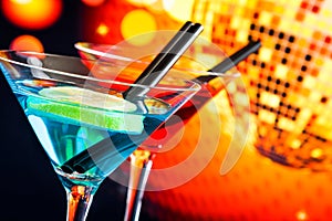 Blue and red cocktail with sparkling disco ball background with space for text