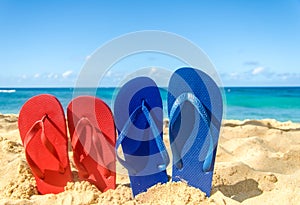 Blue and red flip flops on the sandy beach