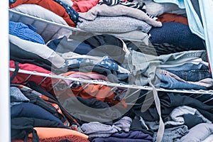 Blue and red hues of clothing in a woman`s closet, folded but messy, in need of closet organization. Depicting donating clothes, t photo