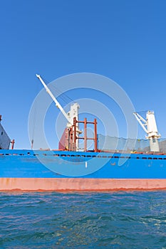 Blue and red hull of ship with white crane 1