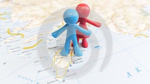 A blue and red rubber toy couple standing on the island of Rhodes on a map of Greece