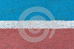 Blue - red tartan surface of athletics stadium with white horizontal line