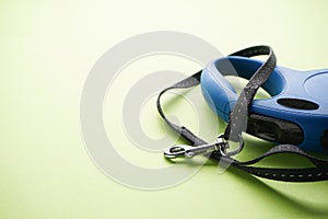 Blue retractable dog leash on a green background, close-up. Space for text