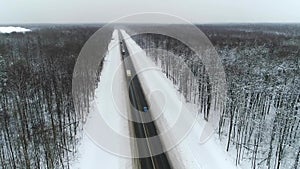 Blue retro car and trucks are riding on a road in winter forest. Aerial view.