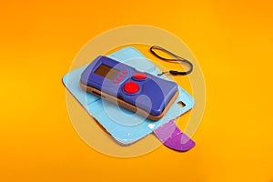 Blue retro electronic portable game console on orange background.