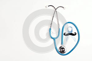 Blue ribbon with mustache and stethoscope on white background. Prostate cancer awareness. Copy space