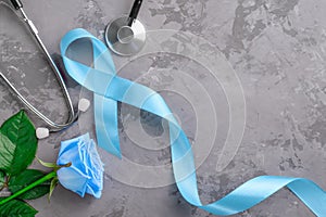 Blue ribbon, stethoscope and rose on concrete background, prostate cancer awareness concept.