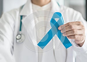 Blue ribbon symbolic for prostate cancer awareness campaign and men`s health in doctor`s hand