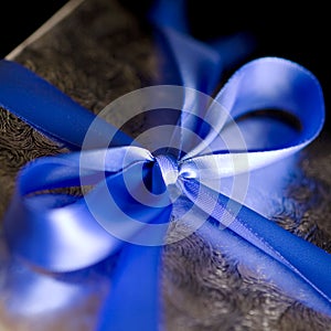 Blue Ribbon Tied in a Bow on Silver Gift.