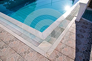 Blue ripped water in swimming pool in tropical resort with edge of pavement. Part of Swimming pool bottom background.