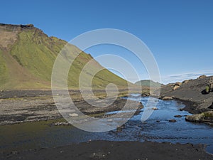 Blue river stream and green Hattafell mountain in Volcanic landscape behind Emstrur camping site in area of Fjallabak