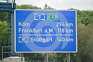 Blue road sign between Cologne, Frankfurt am Main and Stuttgart