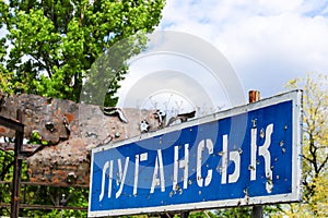 Blue road sign with the inscription in Ukrainian Lugansk, punched by bullets during the war in the Donbass, conflict East Ukraine photo