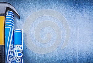 Blue rolled blueprints claw hammer on metallic background copysp