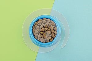 Blue round feeding bowl with dark brown heart shaped pet kibble