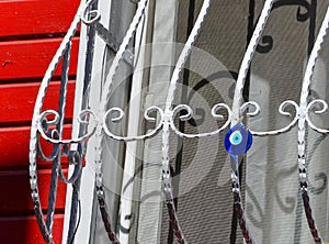 Blue round glass pendant in the form of an eye hanging on a lattice window. Traditional Turkish amulet - Nazar boncuk photo