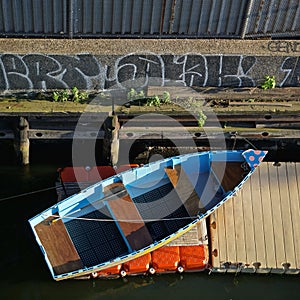 Blue rowboat on a red mat next to a yellow dock