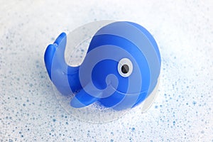 Blue rubber whale on white soap foam